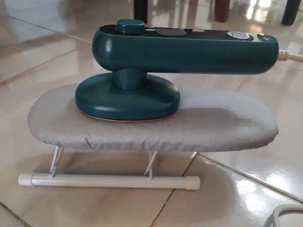 Mini Ferro de Passar compacto ao lado de roupa perfeitamente alisada