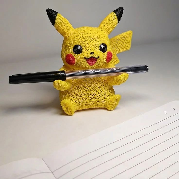 Esculturas 3D coloridas terminadas encima de un escritorio junto a cuadernos escolares