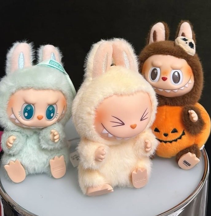 Flat-lay de la caja Labubu Monsters abierta con la bolsa interior sellada revelada y carta de colección al lado