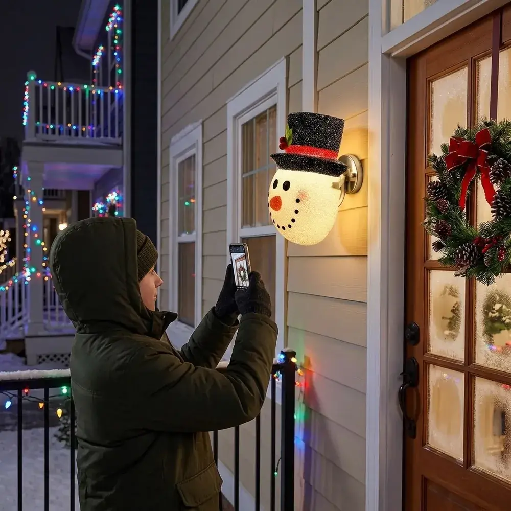 Entrada de prédio à noite com o boneco de neve aceso no candeeiro ao lado da porta e vizinhos a passar