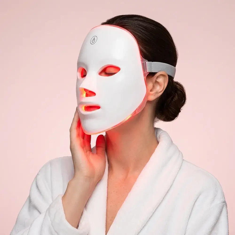 Donna in accappatoio bianco con la maschera LED accesa in rosso